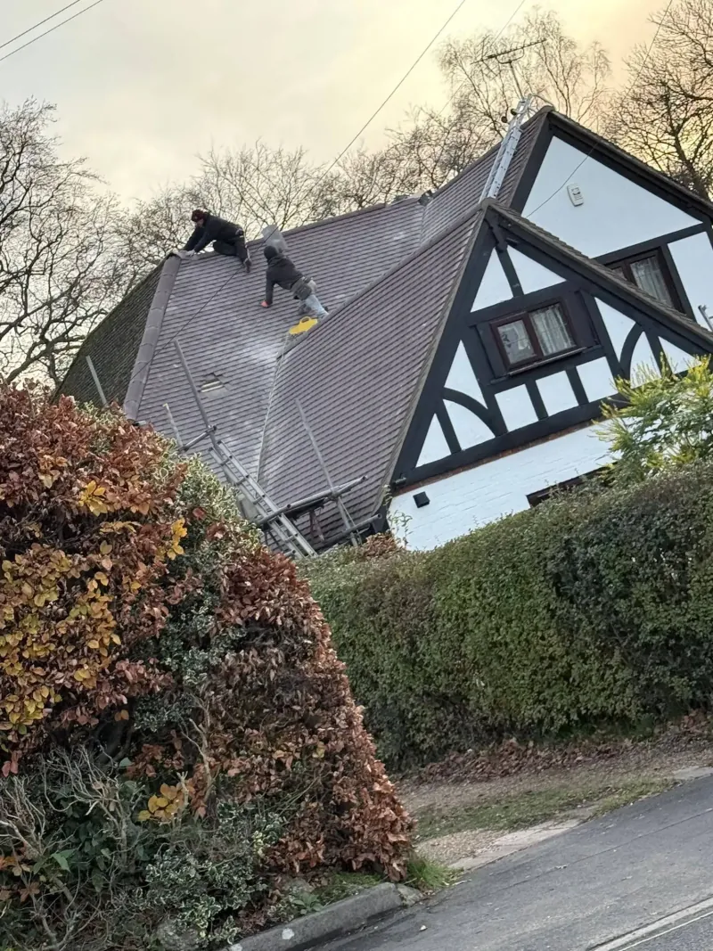 Roofer carrying out slate repairs on a pitched roof in Ascot